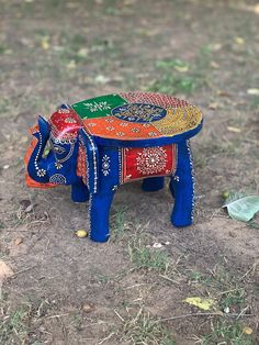 an elephant made out of different colors on the ground with grass and leaves in the background