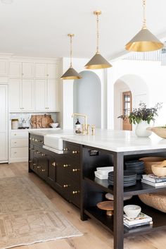 a large kitchen with white cabinets and gold pendant lights hanging from the ceiling over the island