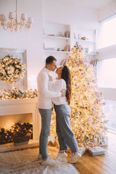 a man and woman kissing in front of a christmas tree