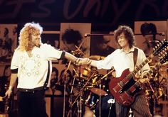 two men shaking hands on stage with guitars