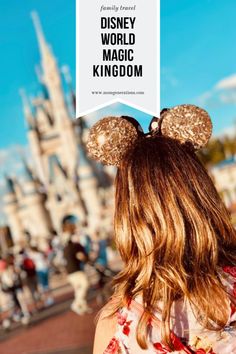 the back of a woman's head with minnie mouse ears in front of a castle