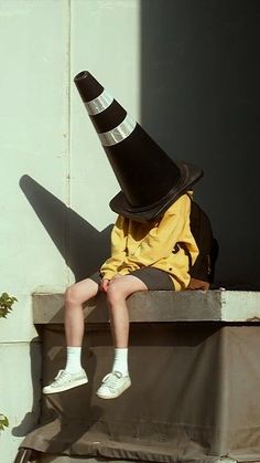 a young boy wearing a black and white hat sitting on top of a cement block