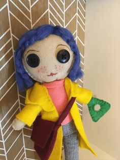 a stuffed doll with blue hair wearing a yellow jacket