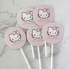 four pink hello kitty lollipops sitting on top of a marble countertop