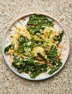 a white plate topped with spinach and other food on top of a countertop