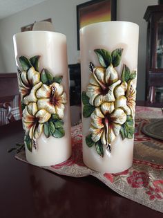 two candles with flowers painted on them sitting on a table