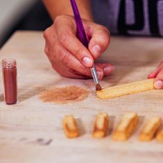 a person is using a pencil to draw something on a piece of wood that has been cut into smaller pieces