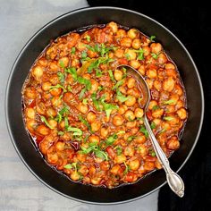 a black bowl filled with chickpeas and spinach on top of a table