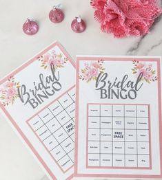 the bridal bingo game is next to some pink ornaments on a white marble table