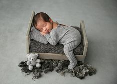 a baby sleeping in a wooden crate with a stuffed animal on the floor next to it