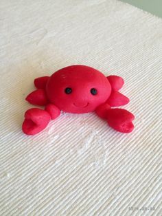 a red toy crab laying on top of a white blanket