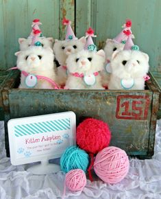 four stuffed animals are in a box with yarn and balls of yarn next to it