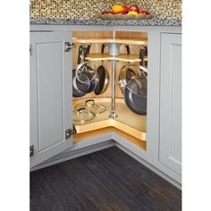 an open kitchen cabinet with pots and pans in the bottom half, on top of a countertop