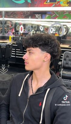 a young man with black hair sitting in front of a table and looking off to the side