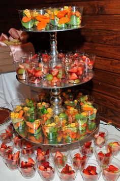 a three tiered tray filled with glasses and fruit