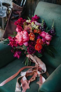 a bouquet of flowers sitting on top of a green chair next to a brown ribbon