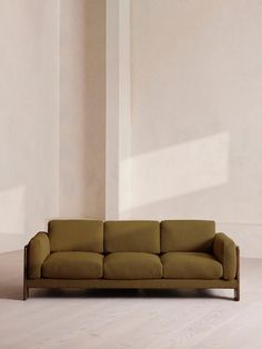 a brown couch sitting on top of a hard wood floor next to a white wall