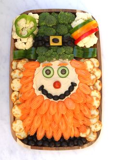 a platter with vegetables, cauliflower, broccoli and a face made to look like a lion