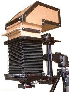 an old fashioned camera sitting on top of a tripod next to a white background