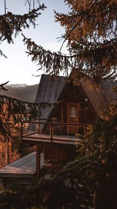 a wooden cabin in the woods with mountains in the background