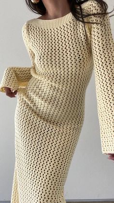 a woman in a yellow knitted dress with her hands on her hip and the bottom half of her body