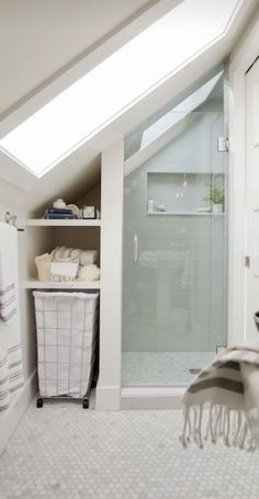 an attic bathroom with skylight and white tile flooring, along with a walk - in shower