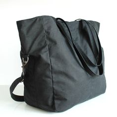 "Black 2 Way Waxed Canvas Tote MATERIALS Exterior fabric: 100% black waxed cotton canvas (British) Lining fabric: 100% cotton twill (Italian) APPROXIMATE DIMENSIONS Width: 35.5cm / 14\" Depth: 17cm / 6.75\" Height: 36cm / 14\" Shoulder strap length: adjustable from 75cm to 136cm / 29.5\" to 53.5\" Interior zipper pocket: 25cm / 10\" W x 21.5cm /8.5\" H Interior sleeve pocket 1: 9cm /3.5\" W x 15cm / 6\" H x 2cm / 0.75\" D Interior sleeve pocket 2: 8cm /3.25\" W x 15cm / 6\" H x 2cm / 0.75\" D DE Functional Black Canvas Bag With Leather Handles, Functional Black Canvas Bag For Everyday, Black Canvas Weekender Bag For Everyday, Black Duffle Bag With Pockets For Everyday Use, Black Waxed Canvas Tote Shoulder Bag, Everyday Black Canvas Bag With Zipper Closure, Black Canvas Bag With Zipper For Everyday Use, Practical Black Canvas Bag, Black Waxed Finish Shoulder Bag For Everyday