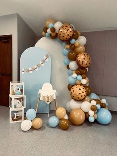 a balloon arch is decorated with blue, gold and white balloons for a baby's first birthday