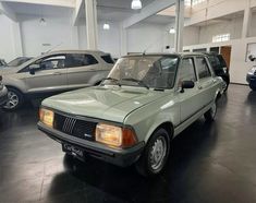 an old green car is parked in a garage next to other cars and suvs