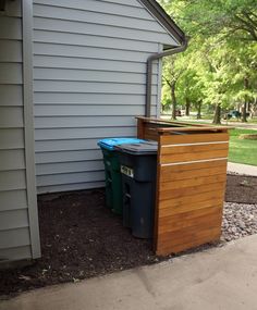 two trash cans sitting next to each other in front of a house