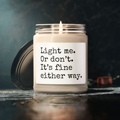 a candle that is sitting on a table with the words light me or don't it's fine either way