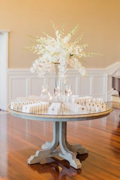 a centerpiece with candles and flowers on a table in the middle of a room