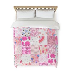 a bed with pink and white quilts on top of it, next to pillows