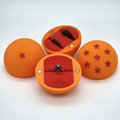 an orange ring box with three rings in it and four red stars on the inside