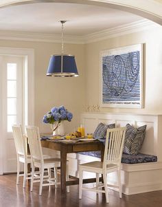 a dining room table with white chairs and a blue lamp hanging from the ceiling over it