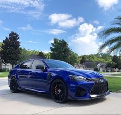 a blue sports car parked in front of a house on a driveway with palm trees