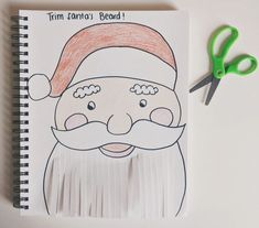 a notebook with a drawing of a santa clause on it next to scissors and paper clippings