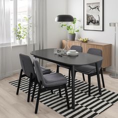 a dining room table with chairs and a rug on the floor