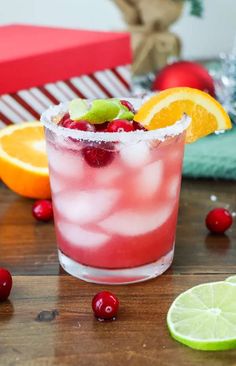 a red drink with oranges, lime and cranberries on a table next to other fruit