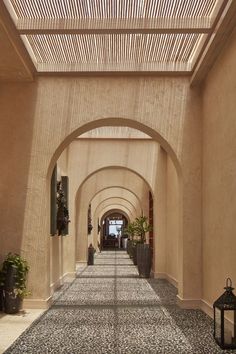 an arched walkway with potted plants on either side and lanterns hanging from the ceiling