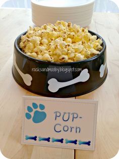 a dog bowl filled with popcorn next to a sign that says pop corn on it