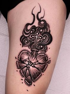 a black and white tattoo on the leg of a woman with a cross in her heart