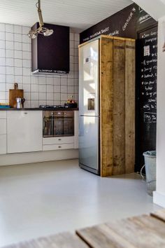 a kitchen area with a refrigerator, sink and stove top oven next to a wall mounted chalkboard