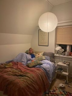 a person laying in bed under a lamp