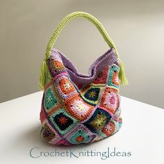 a crocheted purse with tassels and fringe on the handle is sitting on a table