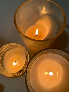 three lit candles sitting in glass bowls on a table