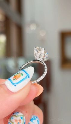 a woman's hand holding a diamond ring with blue and white designs on it