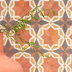 a pink vase sitting on top of a table next to a wall covered in tiles