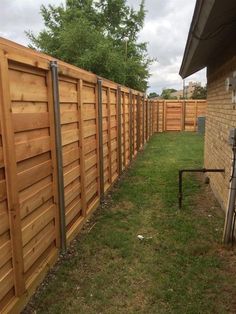 a wooden fence is next to a brick building and green grass in front of it