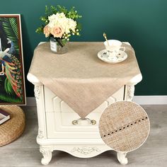 a table topped with a vase filled with flowers next to a painting and a chair